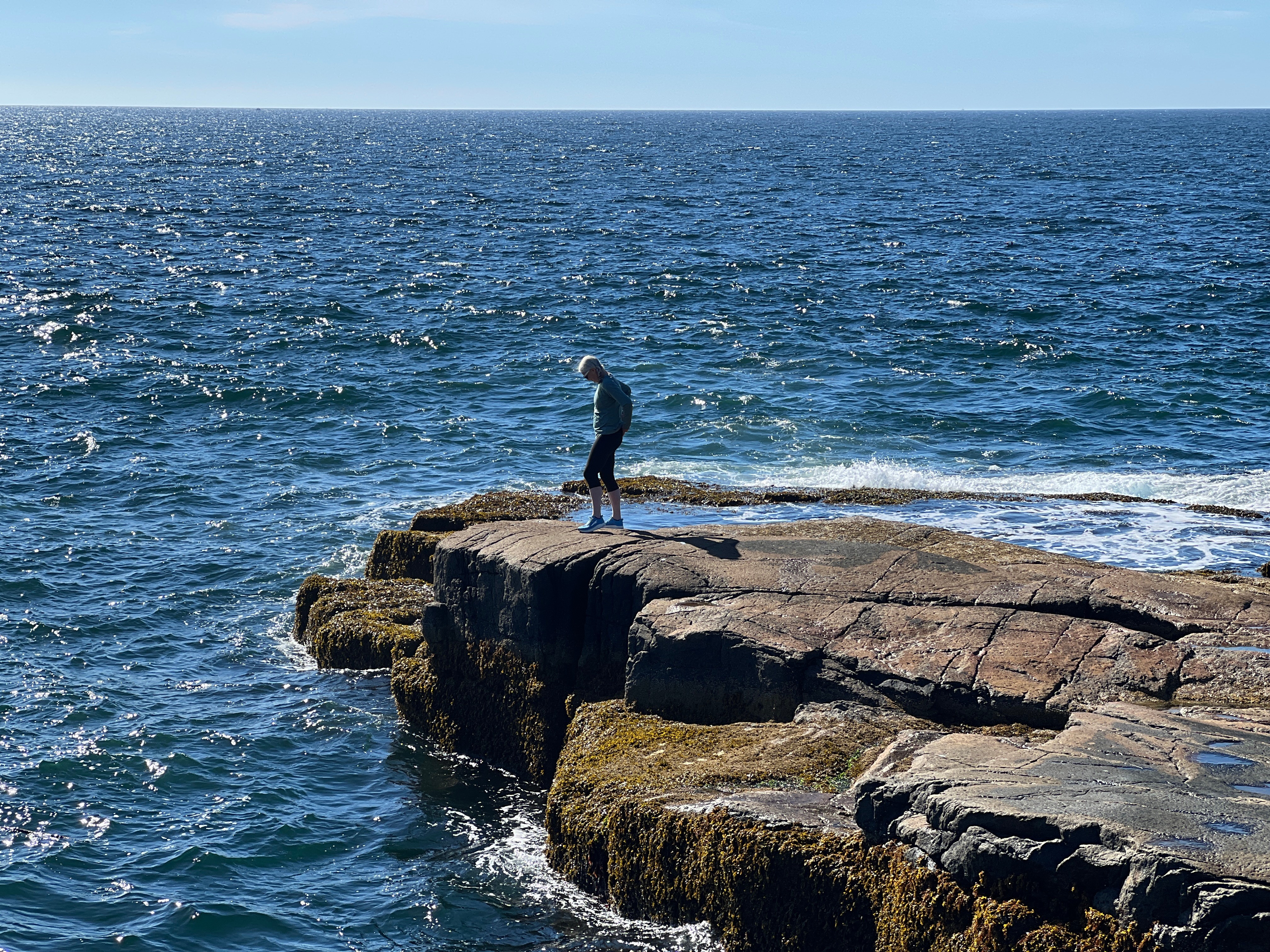 Katie on rocks in the ocean (from a distance)